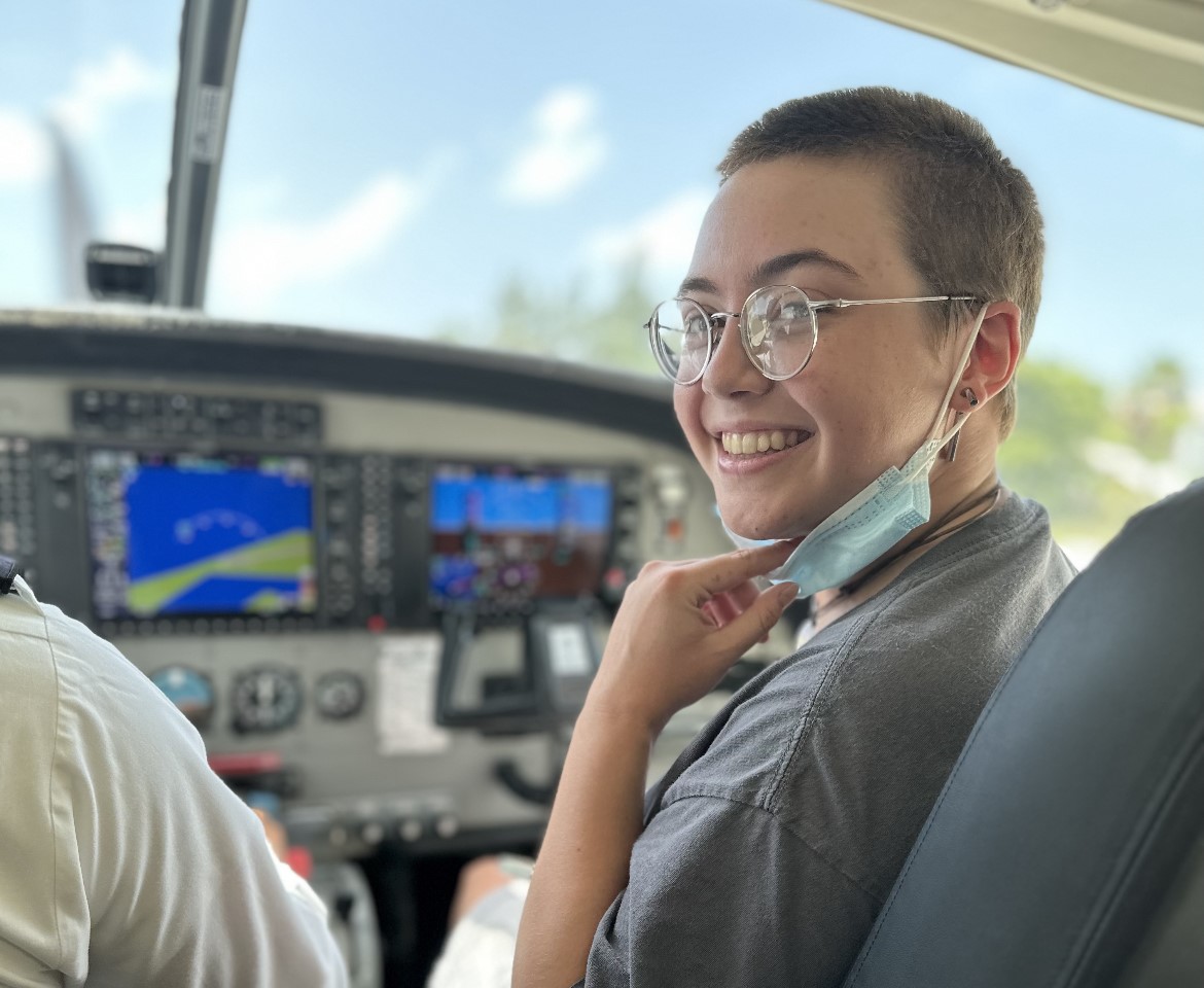 A student sitting in a cockpit.